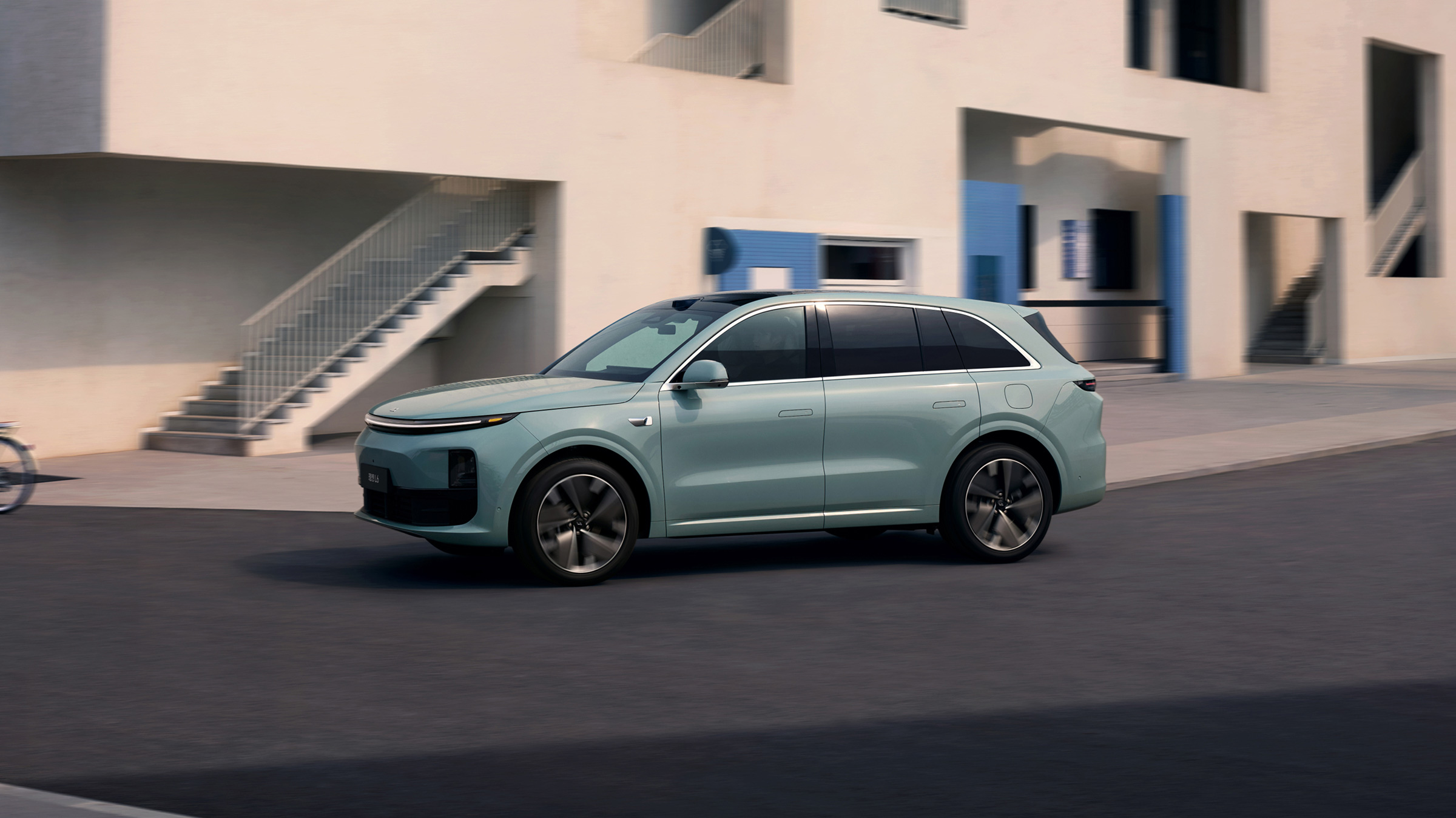 Li Auto L6 verde junto a una residencia de arquitectura contemporánea